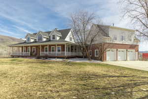 Farmhouse-style home with a large porch, brick siding, a front yard, and a chimney