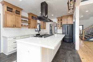 Kitchen with glass insert cabinets, island exhaust hood, high quality fridge, light stone counters, and a center island
