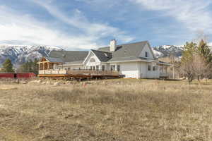 Back of house with a deck with mountain view and a chimney