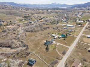 Aerial view of property and surrounding area featuring a mountainous background and rural landscape