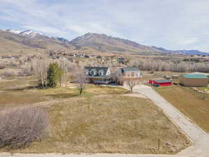 View of front of house with concrete driveway, a mountain view, a rural view, and a front yard