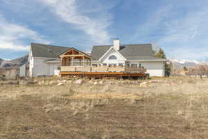 Rear view of property with a deck with mountain view, a chimney, and roof with shingles
