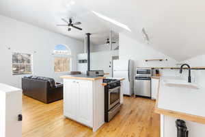 Kitchen featuring light countertops, a skylight, lofted ceiling, stainless steel appliances, and white cabinets