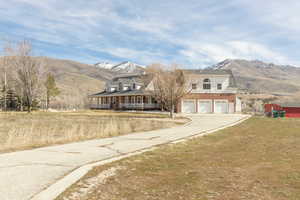 View of front of property with a porch, a mountain view, driveway, a garage, and a front lawn