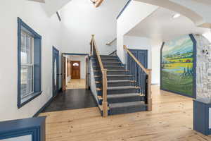 Stairway with wood-type flooring, arched walkways, and a high ceiling