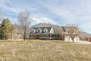 View of front facade featuring a mountain view, covered porch, a front lawn, and a garage