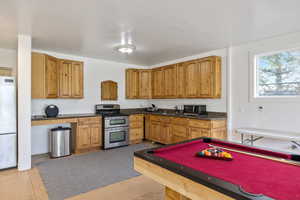 Kitchen featuring double oven range, billiards, freestanding refrigerator, black microwave, and wood finish cabinetry