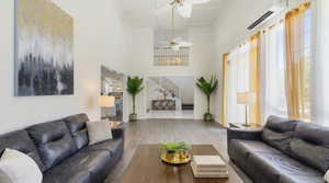 Living area featuring wood finished floors, ceiling fan, a high ceiling, and crown molding