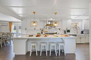 Kitchen with a kitchen bar, a kitchen island, white cabinets, and dark wood-style floors