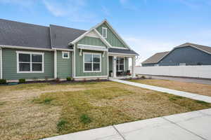 View of front of house with board and batten siding, roof with shingles, and covered porch