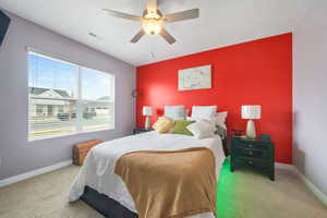 Bedroom with ceiling fan, carpet flooring, and an accent wall