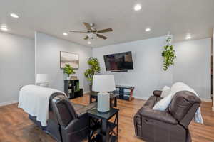 Living room with light wood-style floors, a ceiling fan, and recessed lighting