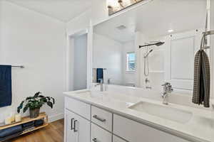 Full bathroom with double vanity and light wood-type flooring