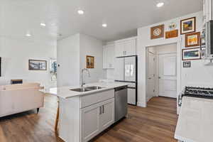 Kitchen featuring open floor plan, a center island with sink, white cabinetry, stainless steel appliances, and recessed lighting