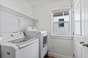 Laundry room with washer and clothes dryer and dark wood finished floors