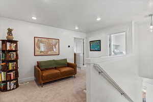 Sitting room with light colored carpet, an upstairs landing, recessed lighting, and washer / dryer