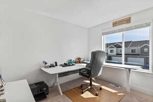 Home office with light colored carpet and baseboards
