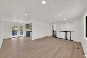 Unfurnished living room with french doors, light wood-style flooring, and recessed lighting