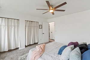 Bedroom with carpet floors, ceiling fan, and two closets