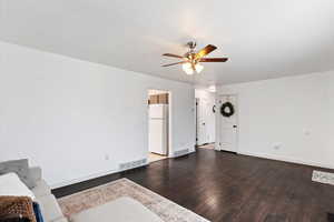 Living room featuring dark wood-type flooring and ceiling fan