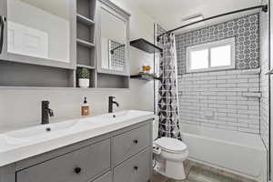 Full bath with double vanity and shower / bath combination with curtain