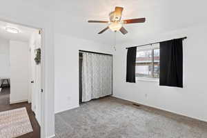 Unfurnished bedroom with a closet, carpet, and ceiling fan