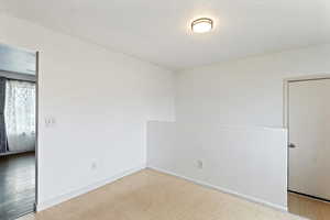 Unfurnished room with light flooring and baseboards