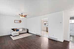 Unfurnished living room with plenty of natural light, dark wood-type flooring, and ceiling fan