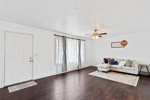 Living area with dark wood finished floors and a ceiling fan