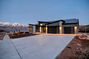 Contemporary home with a mountain view, a garage, concrete driveway, and stone siding