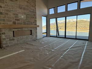 Unfurnished living room featuring a fireplace, a high ceiling, and a water and mountain view