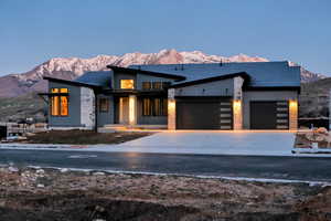 Contemporary house with a mountain view, an attached garage, concrete driveway, and covered porch