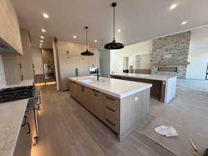 Two tone kitchen with a fireplace, light stone countertops, built in appliances, and two tone cabinetry