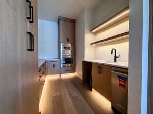 Kitchen with modern cabinets, stainless steel appliances, light stone countertops, and light wood finished floors