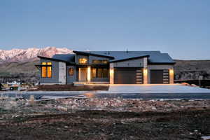 Contemporary home featuring an attached garage, a mountain view, driveway, and a patio