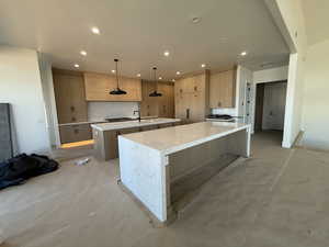 Kitchen featuring light wood finish cabinets, light stone counters, tasteful backsplash, concrete floors, and a breakfast bar area
