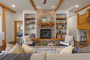 Living area with wood finished floors, a fireplace, beamed ceiling, and ceiling fan