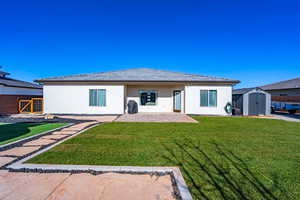 Rear view of house featuring a storage unit, stucco siding, and a patio area