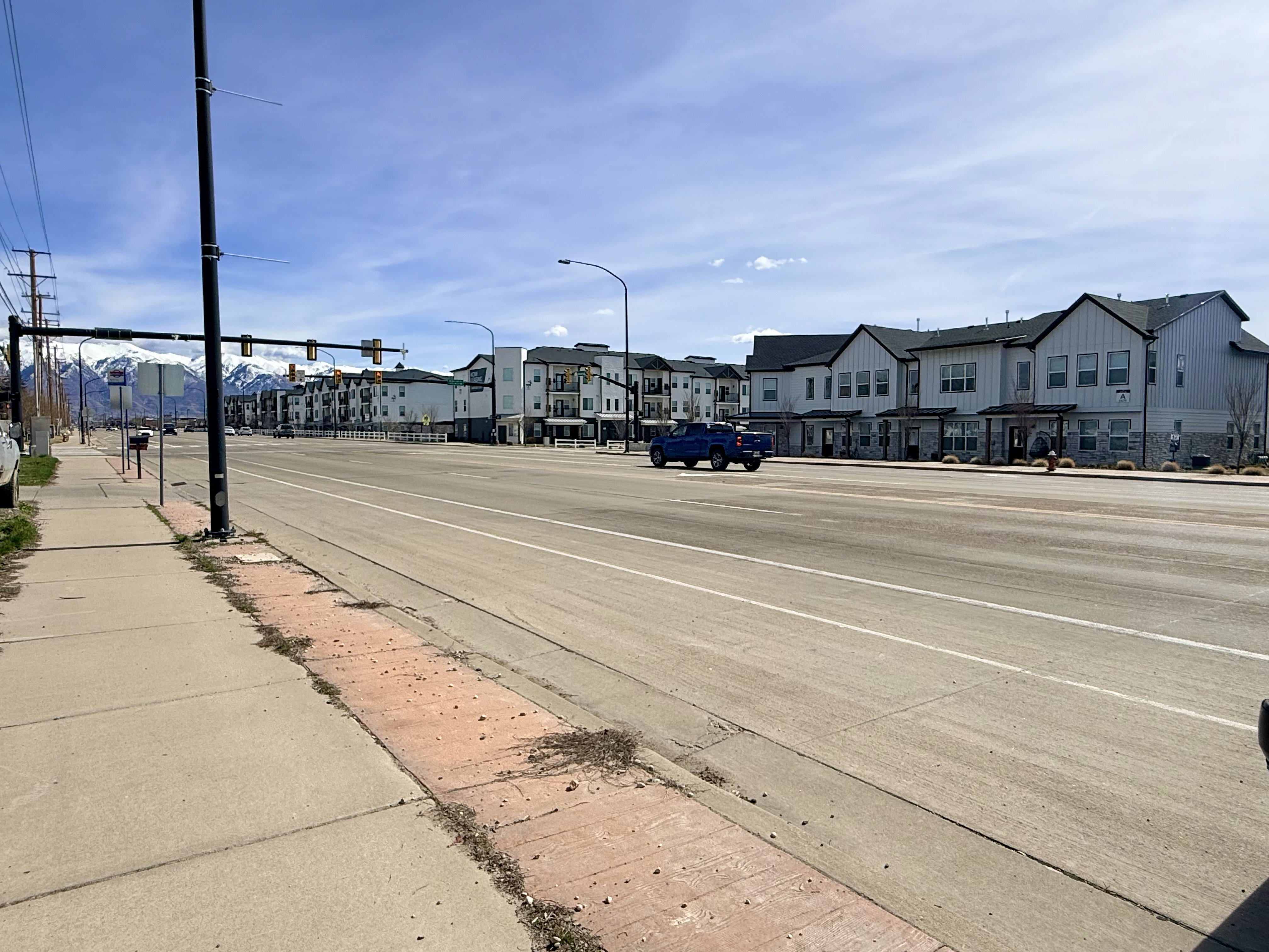 View of concrete road featuring sidewalks, street lighting, traffic lights, a residential view, and curbs