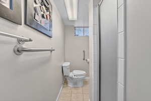 Bathroom featuring a textured ceiling, a stall shower, and light tile patterned floors