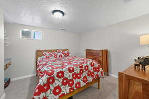 Bedroom with a textured ceiling and light carpet