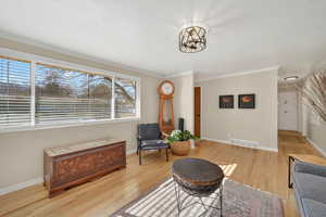 Sitting room with light wood finished floors and ornamental molding