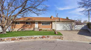Ranch-style home featuring concrete driveway, a garage, a chimney, and brick siding