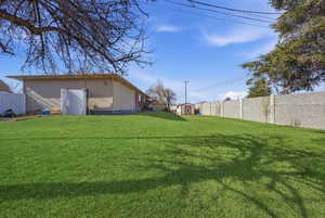 Fenced backyard featuring a shed