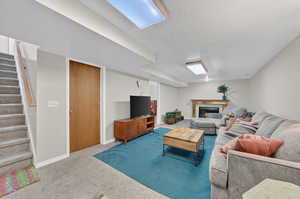 Living room with a tiled fireplace, a textured ceiling, and carpet flooring
