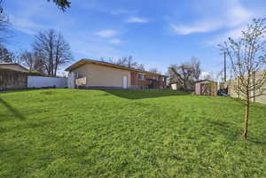 Back of house featuring a storage unit and a fenced backyard