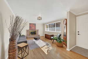 Living room featuring ornamental molding, a glass covered fireplace, and light wood-style floors