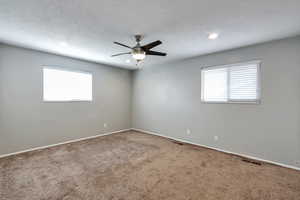 Unfurnished room with carpet floors, ceiling fan, healthy amount of natural light, and a textured ceiling