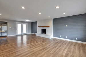 Unfurnished living room with wood walls, light wood finished floors, a fireplace, and recessed lighting