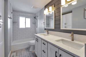 Bathroom with double vanity, shower / tub combination, and wood tiled floors